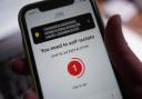 A message to self-isolate, with one day of required isolation remaining, is displayed on the NHS coronavirus contact tracing app on a mobile phone, in London. Picture date: Thursday July 15, 2021..