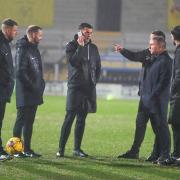 Paul Simpson and match officials discuss the pitch ahead of the postponement