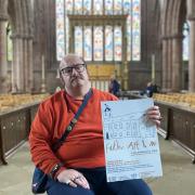 Artist JYMA holding the poster for Faith, Art & Me, due to be displayed in Carlisle Cathedral in May Half Term 2024