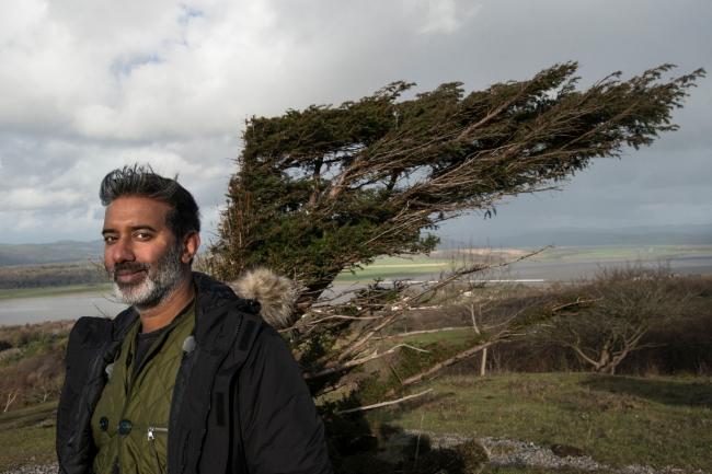 Nihal Arthanayake with a twisted yew tree behind on Arnside Knott, Cumbria. Photo credit: BBC/Winter Walks.