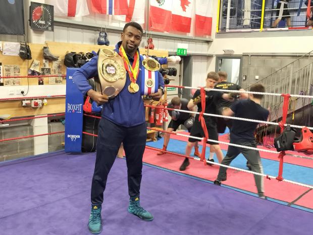 News and Star: Ogbo pictured at Border City ABC with his national title belt, as young fighters spar