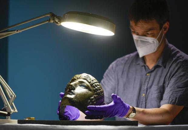 News and Star: ASTONISHING: Dr Fraser Hunter, Senior Curator at the National Museums of Scotland, examines the Newstead mask.  Photo: Stuart Walker
