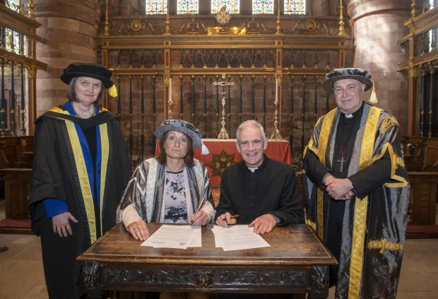 News and Star: University of Cumbria Vice Chancellor Professor Julie Mennell and the Very Revd Mark Boyling, Dean of Carlisle, sign the Memorandum of Cooperation inside Carlisle Cathedral, witnessed by Dr Signy Henderson, Dean for Student Success at the university (left) and University of Cumbria Chancellor the Most Revd and Rt Hon Stephen Cottrell, Archbishop of York (right). 