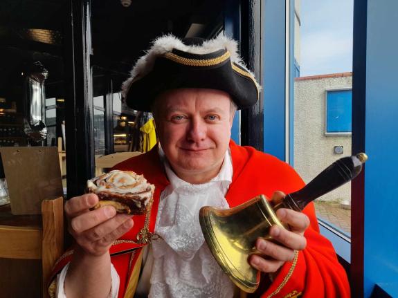 News and Star: The town crier enjoys a cinnamon roll which the cafe is known for News and Star: The town crier enjoys a cinnamon roll which the cafe is known for