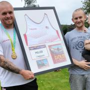 Nick Miller with the framed vest he is using to raise funds to support toddler Oliver Lancaster (right, with dad Michael)
