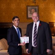 Prime minister Rishi Sunak and Mark Jenkinson posing for a photo with the card, signed by the PM and the Speaker, Lindsay Hoyle