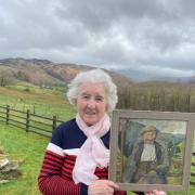Jean Wilson pictured with the painting of Joe Maxwell to same backdrop of The Bank