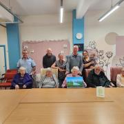 Left to right: Mick, Barry, Gaynor, Dave, Amy, baby Jax, with service users Joyce 84, Isabelle 77, Adrianne 85, Ian 76 and Maxine 88.